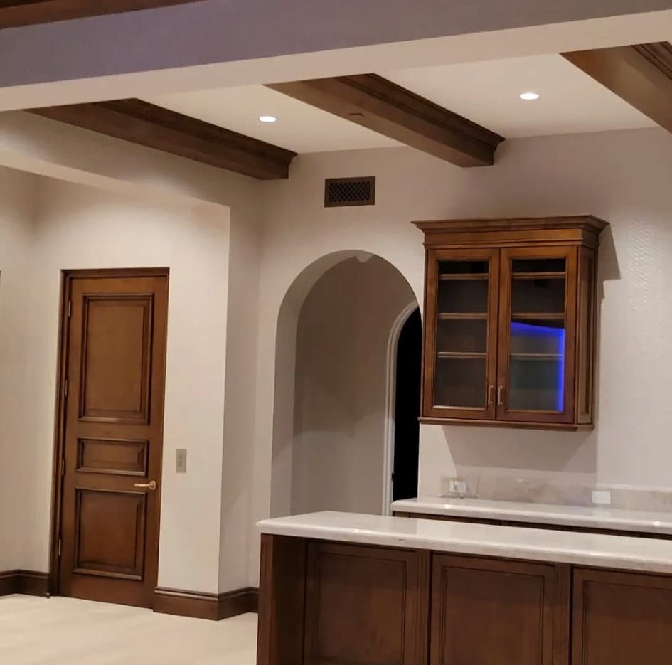 Open kitchen and bar area with subtle textured wall covering and wood beam ceiling