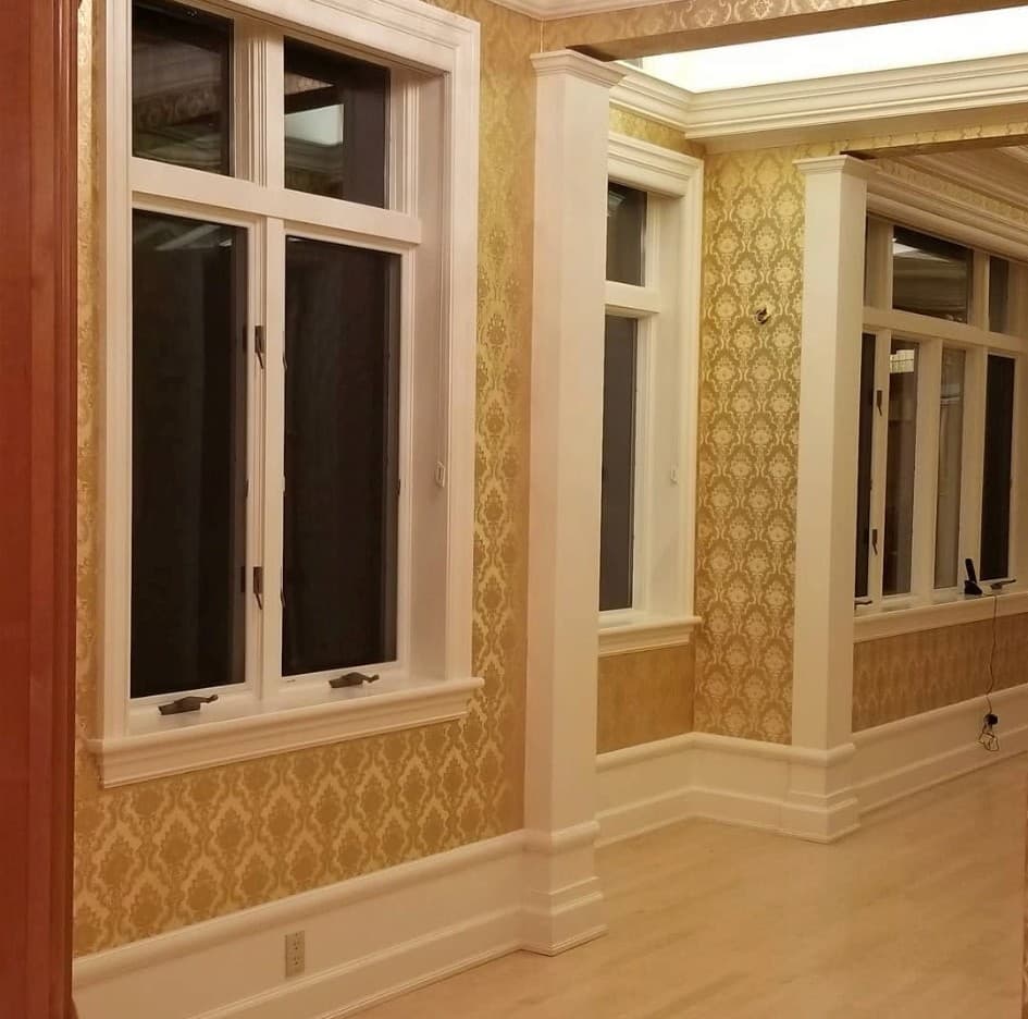Bright room with gold amber damask wallpaper and large multi-pane windows