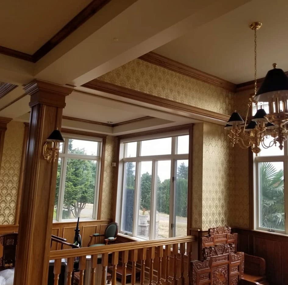 Library with gold damask wallpaper, dark wood columns and decorative railing