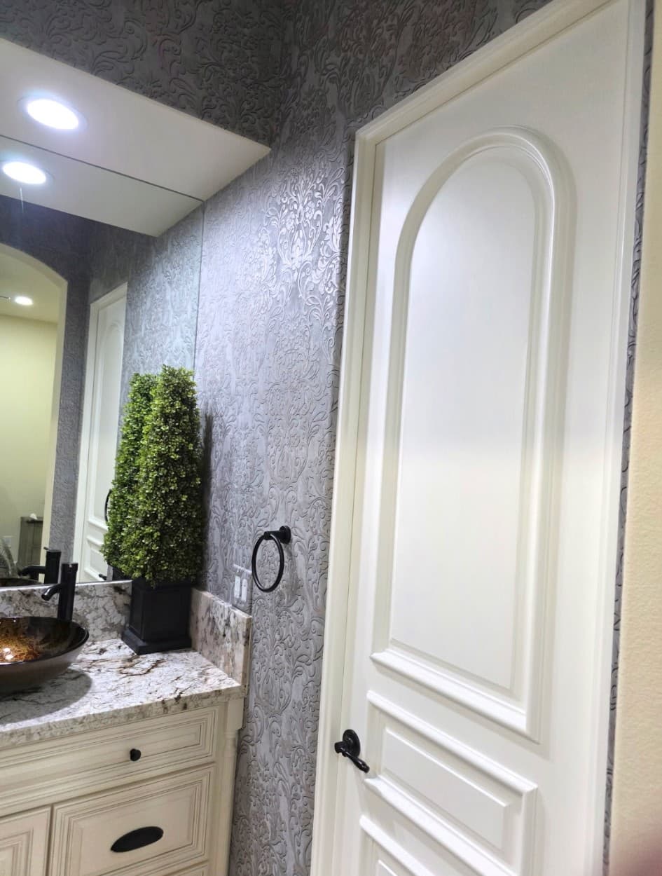 Silver embossed floral damask wallpaper in a powder room with white arched door